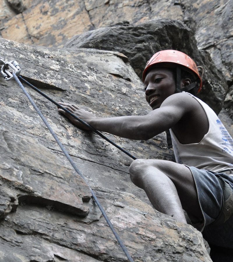 Happy young man scaling a rock face as part of a residential youth treatment program
